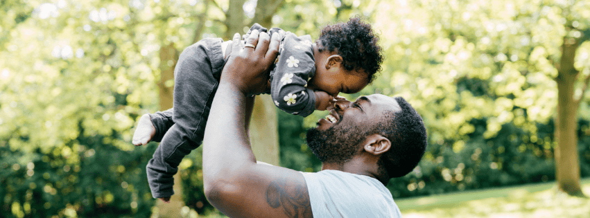a father holding up his child while playing outside