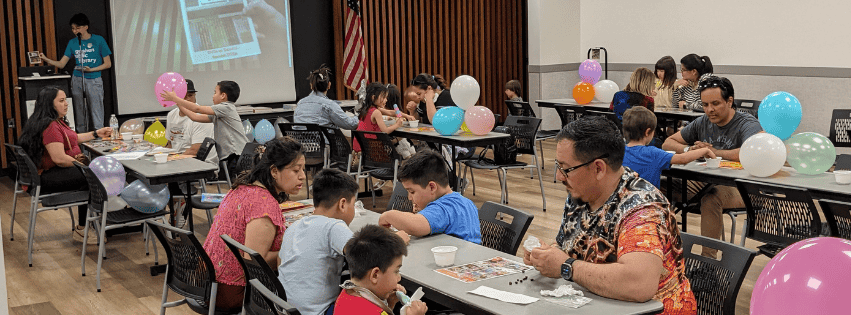 a room full of families sitting at tables playing lotería