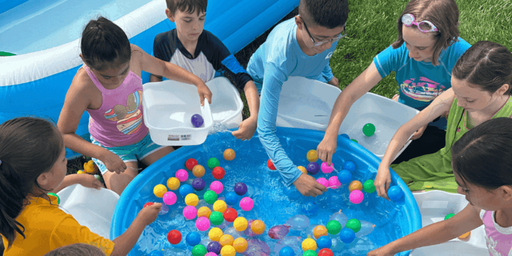 kids playing a game of fishing out balls from a kiddie pool.